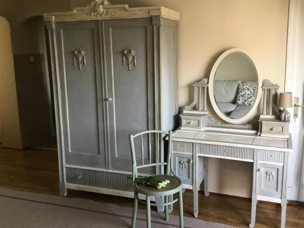 a room with a dresser and a mirror and a chair at Soós Apartman in Balatonfüred