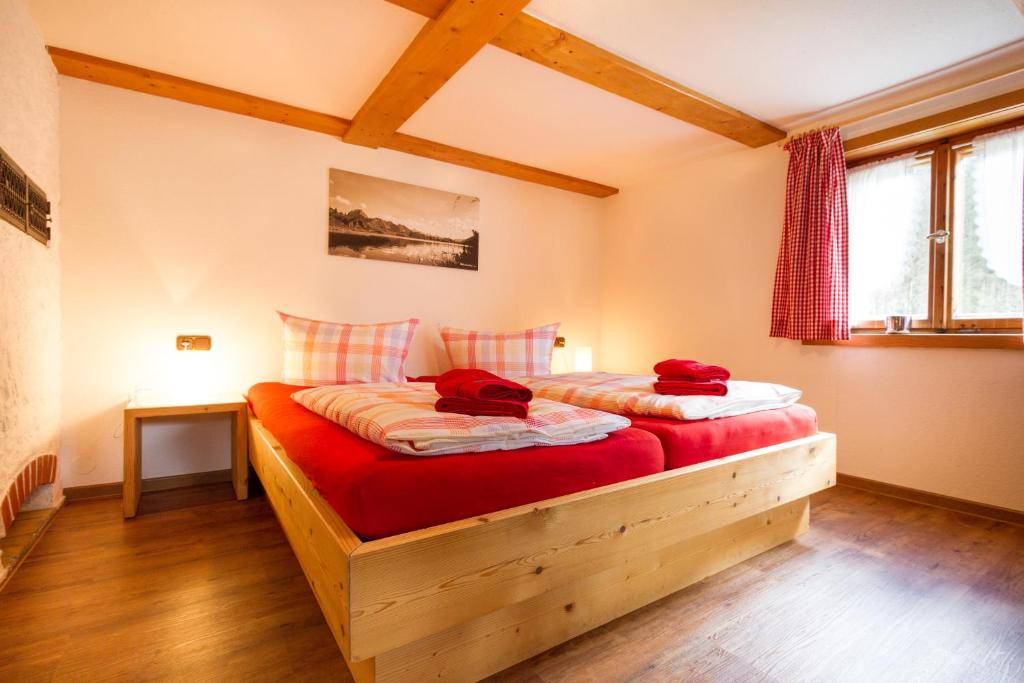 Schlafzimmer mit einem Holzbett mit roter Bettwäsche in der Unterkunft Cafe Christlessee in Oberstdorf