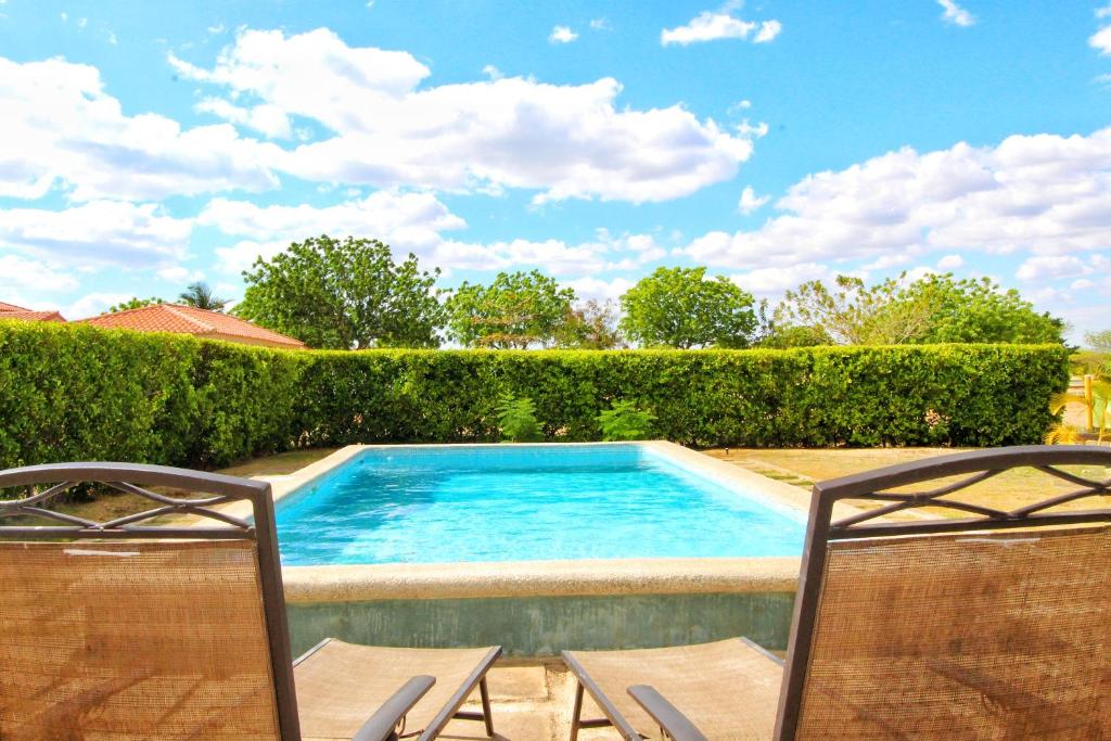 a swimming pool with two chairs next to a hedge at Casa Brisa Gran Pacífica Resort in San Diego