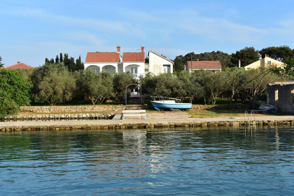 una casa con un barco a orillas del agua en Family House Rebeka en Ugljan