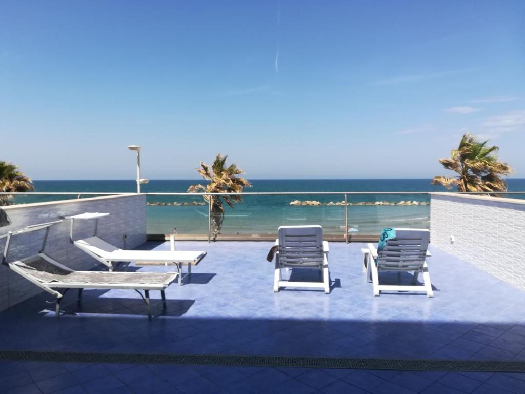 eine Terrasse mit Stühlen, Tischen und Meerblick in der Unterkunft Residence Acqua di Mare in Termoli