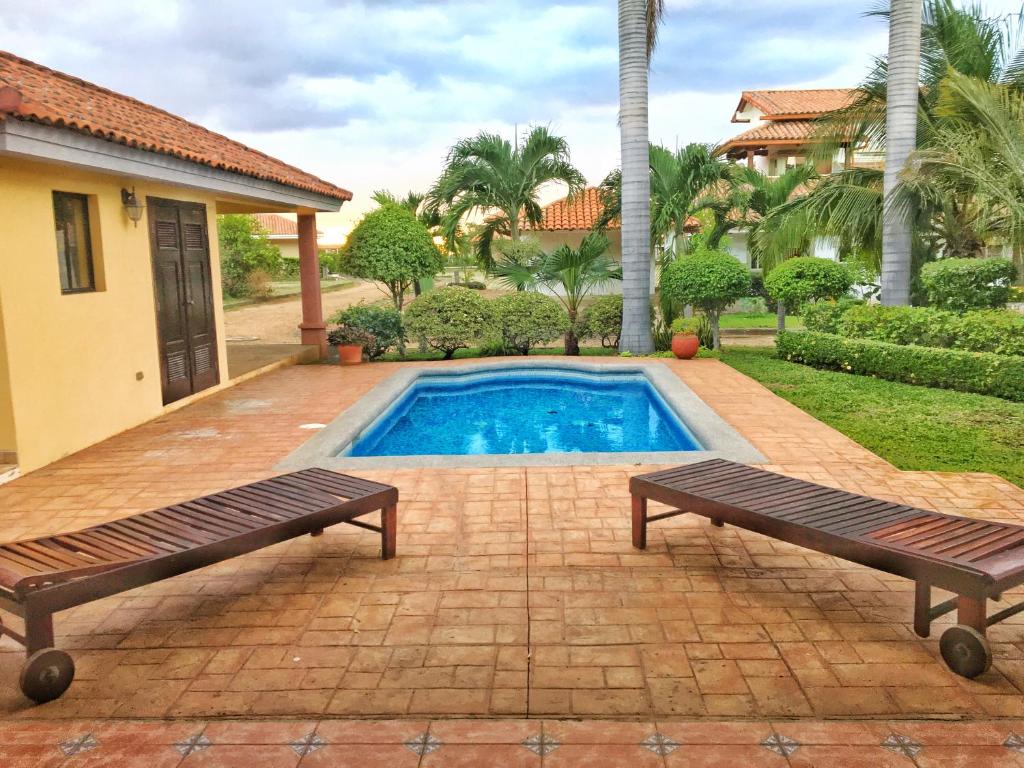 a swimming pool with two benches in front of a house at Casa Carolina Gran Pacífica Resort in San Diego