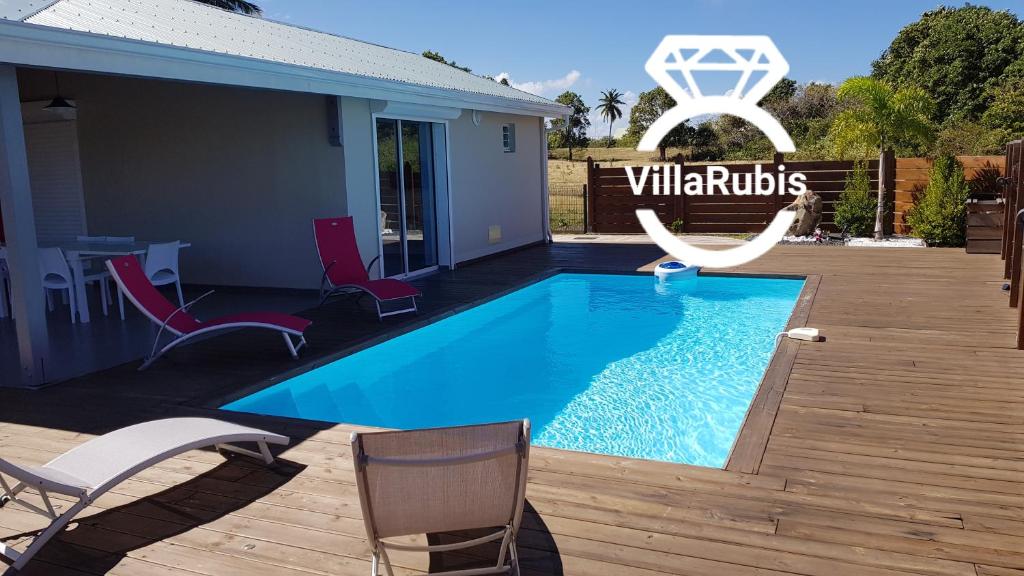 - une piscine avec des chaises et un panneau indiquant les baleiniers dans l'établissement Villa Rubis, à Le Moule