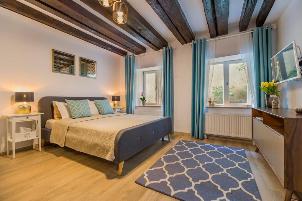 a bedroom with a bed with blue curtains and a television at Uptown Studio Brasov in Braşov