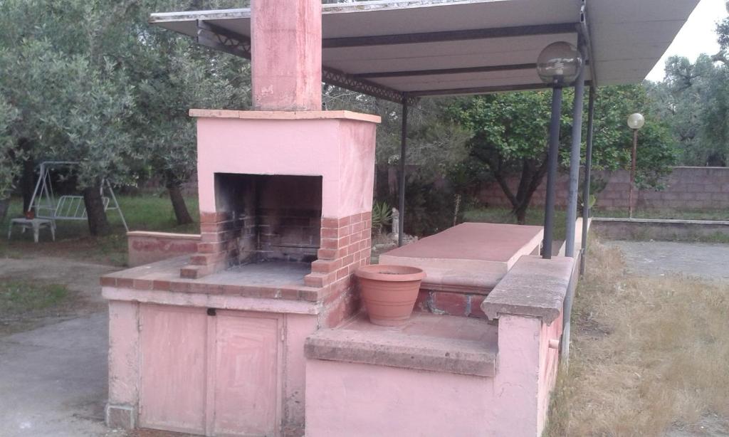 un horno de ladrillo rosa con una mesa y un banco en Villa Rustica, en Nardò