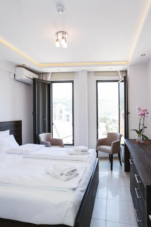 a bedroom with a large bed and two chairs at Arka Budva in Budva