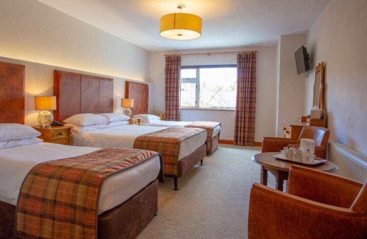 a hotel room with two beds and a table at Lydons Lodge Hotel in Cong