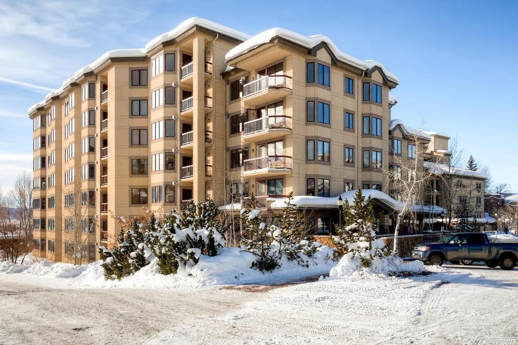 duży budynek apartamentowy ze śniegiem przed nim w obiekcie Torian Creekside III w mieście Steamboat Springs
