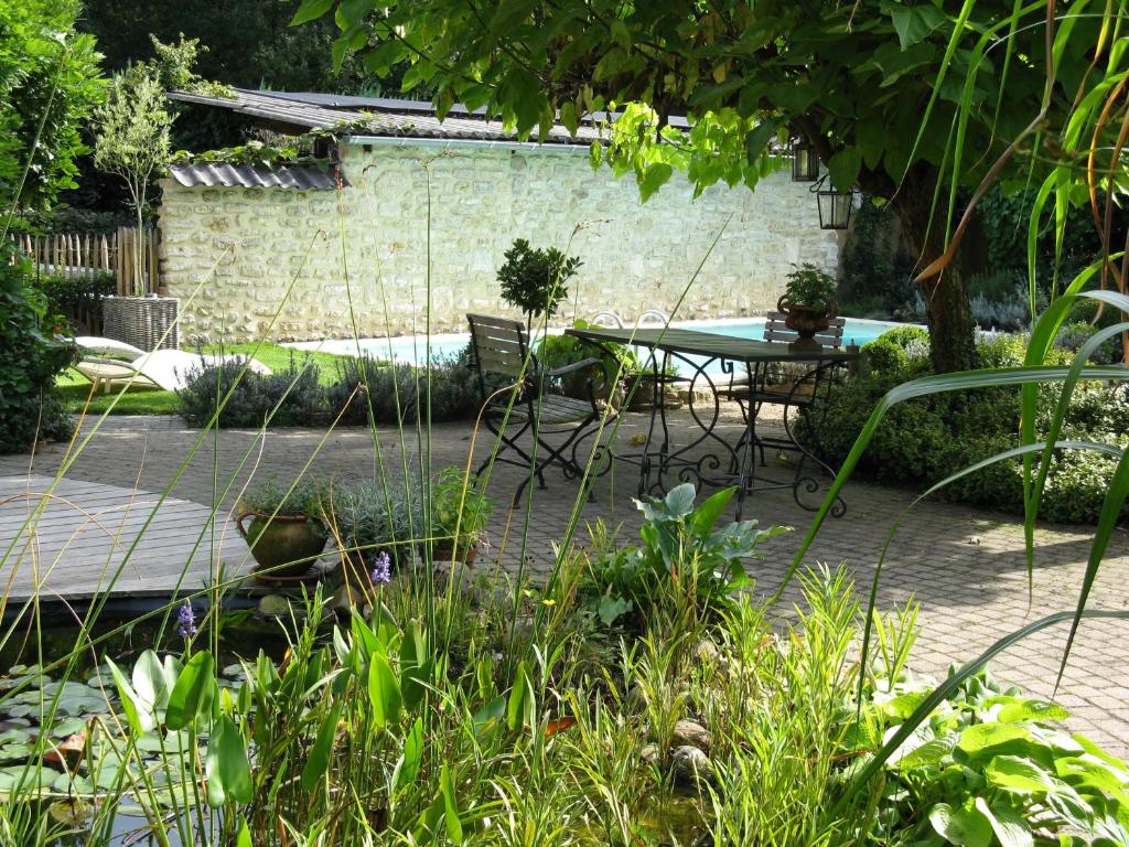 een patio met een tafel en stoelen in een tuin bij De Epicurist in Hasselt