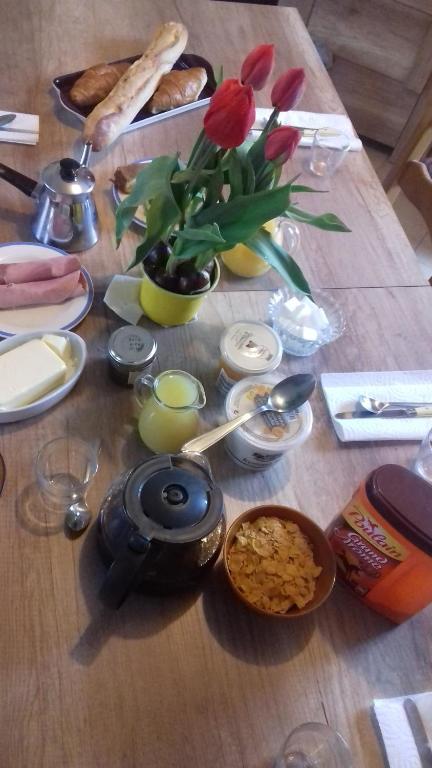 a wooden table with a vase of flowers and food at Chambres d'Hotes Elvire et Laurent Barbey in Sainte-Marie-du-Mont