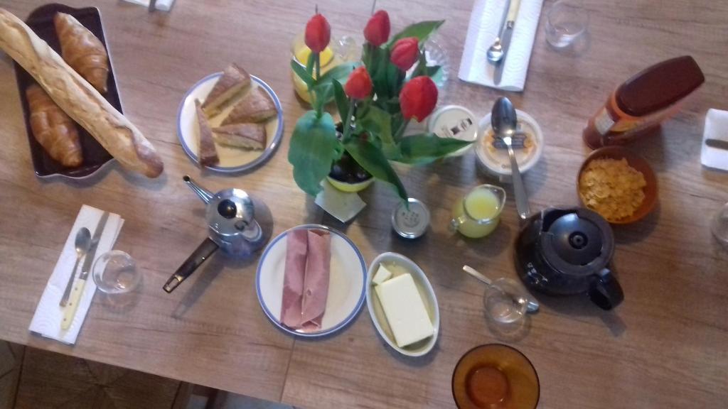 a table with plates of food and a vase of flowers at Chambres d'Hotes Elvire et Laurent Barbey in Sainte-Marie-du-Mont