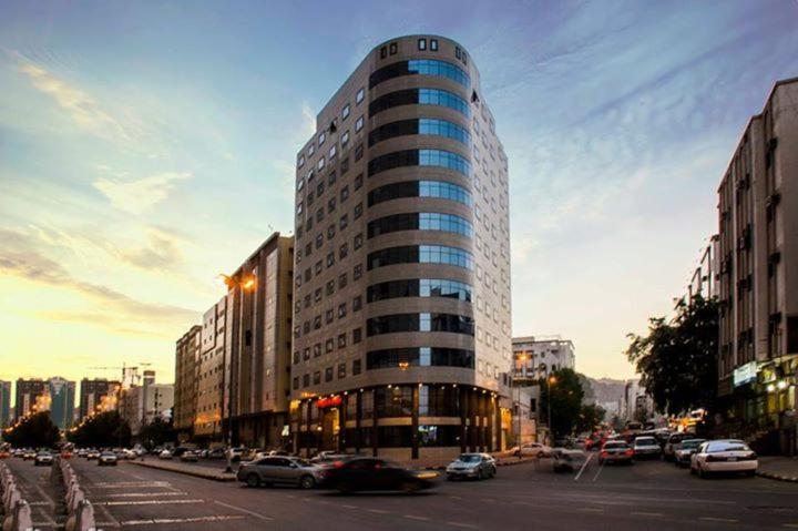 メッカにあるDiyaralmashaer Al-Hadiyah Hotelの車の通る賑やかな街路の高層ビル