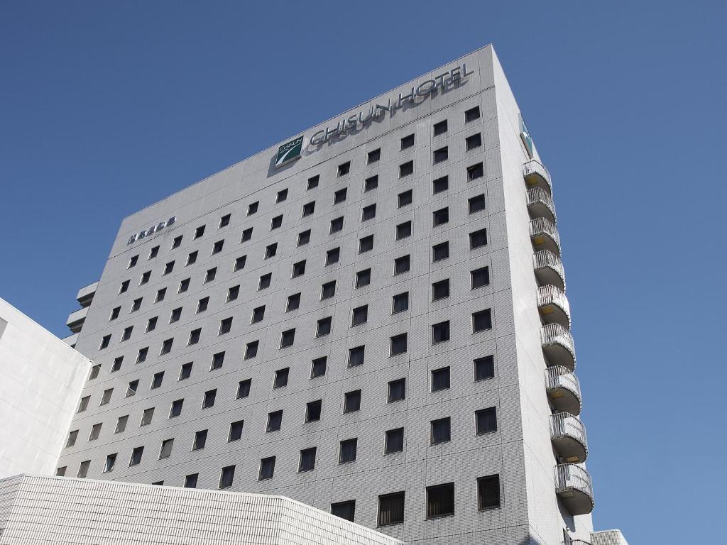 Un alto edificio bianco con un cartello sopra di Chisun Hotel Utsunomiya a Utsunomiya