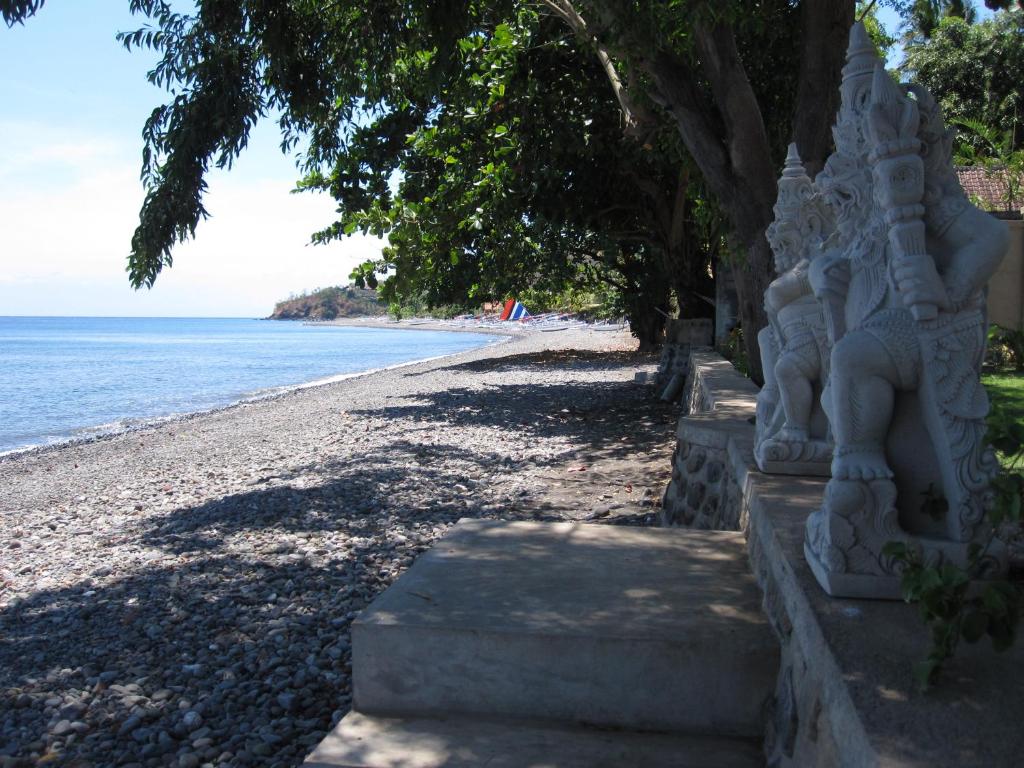 a beach with a stone statue next to the ocean at Bali Dream House in Amed