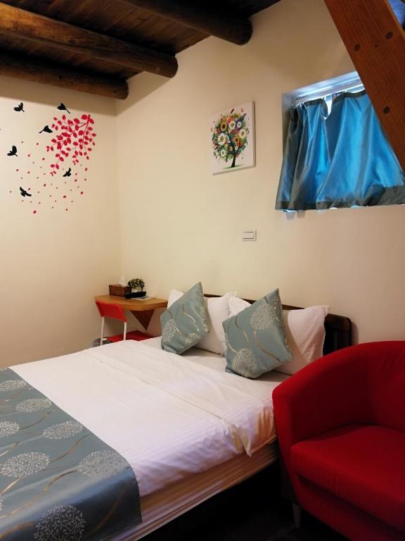 a bedroom with a bed and a red chair at Zhu Shan Grandee B&amp;B in Jincheng