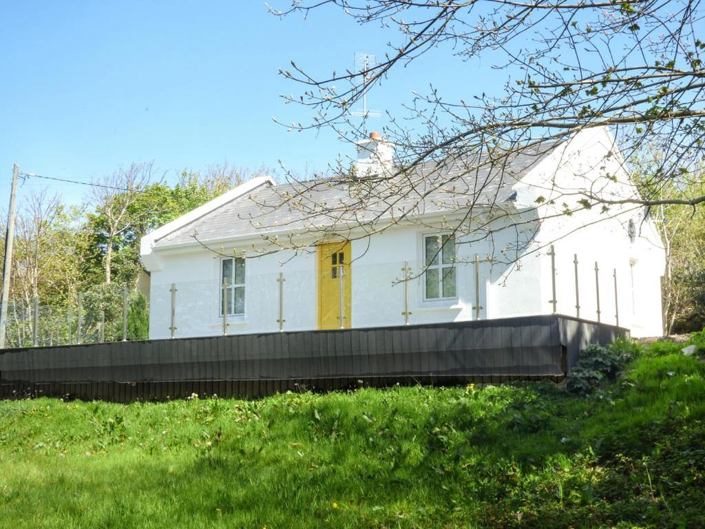 una casa blanca con puerta amarilla en Hidden Gem Cottage, en Dungloe