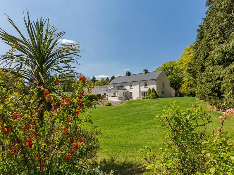 una casa en un césped verde con una palmera en Curradoon House, en Ballynamult