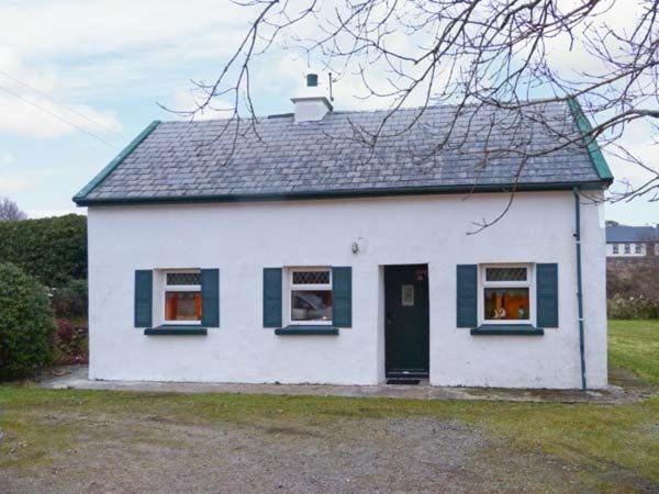 a white house with green windows and a door at The Lake House, Connemara in Knock