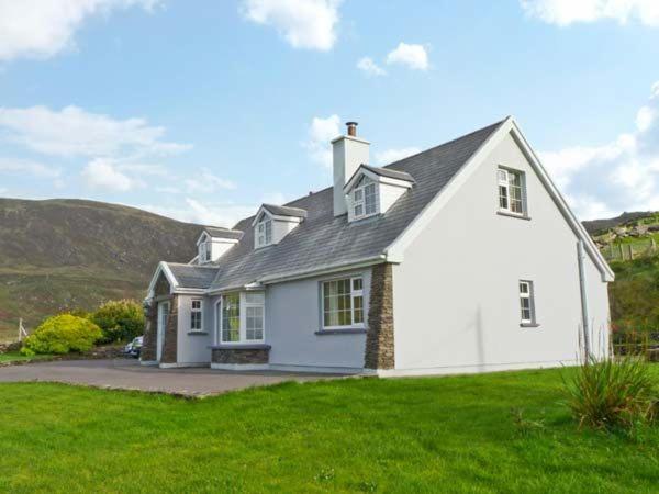 a white house with a hill in the background at Carraig Oisin in Waterville