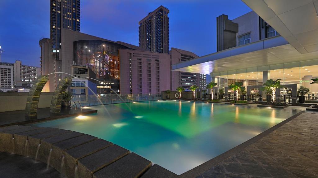 a large pool in the middle of a city at night at Furama Bukit Bintang, Kuala Lumpur in Kuala Lumpur
