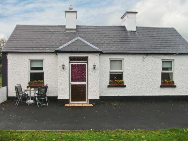 a white house with a table and chairs in front of it at Hazel Cottage in Kilmore