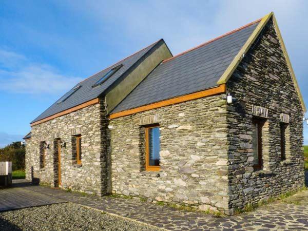 un pequeño edificio de piedra con techo negro en Corr an Droma en Rossbrin