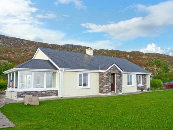 a white house with a green lawn in front of it at Kerry Way Cottage in Coad