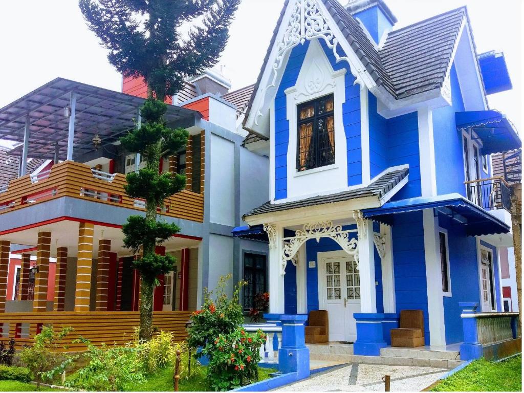 a blue and white house with a palm tree at Zevannya Villa Kota Bunga in Puncak