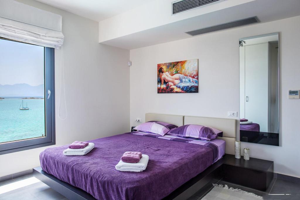 a bedroom with a purple bed with towels on it at Villa Andrea in Elounda
