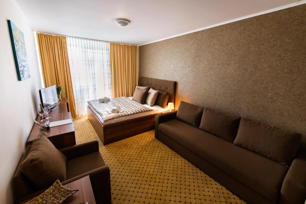 a living room with a couch and a bed at Hotel Merkur in Kaluža