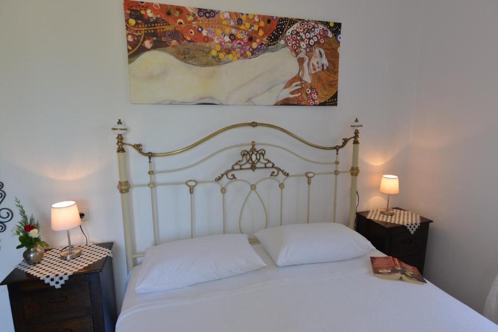 a bedroom with a white bed and a painting on the wall at Haus Katerina in Vourvourou