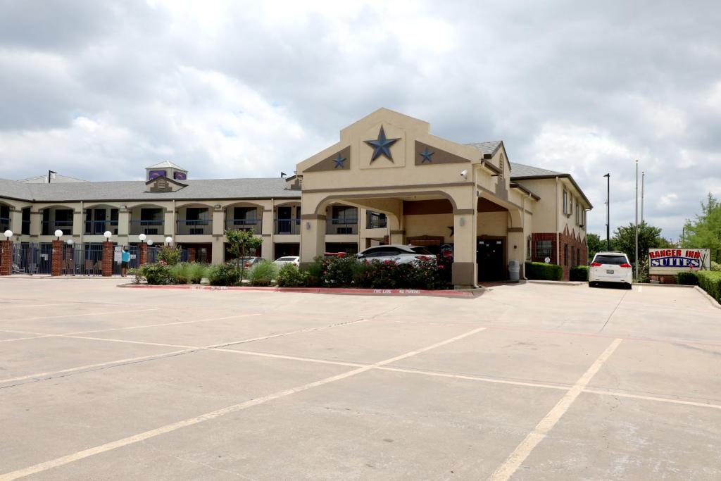 a large building with a parking lot in front of it at Ranger Inn & Suites in Arlington