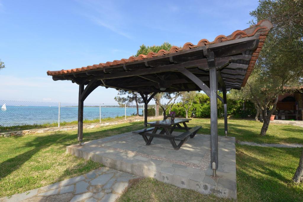 a picnic table under a wooden pavilion next to the ocean at Haus Katerina in Vourvourou