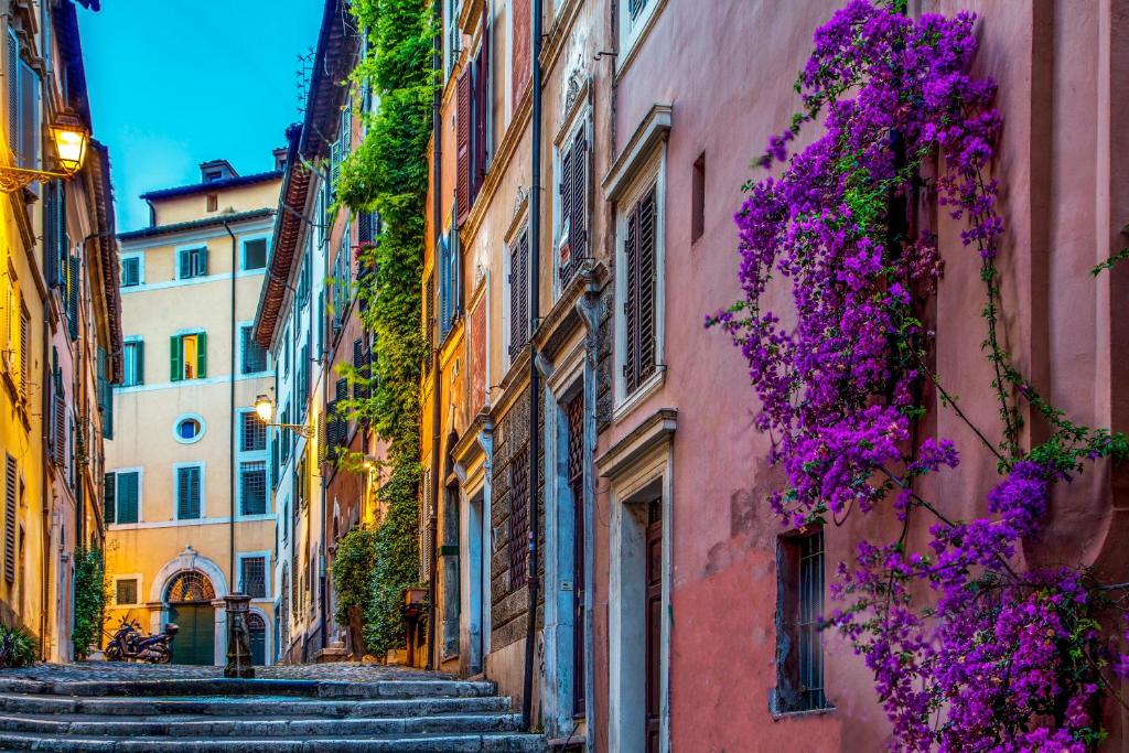 an alley in an old town with purple flowers at The Inn At The Roman Forum in Rome