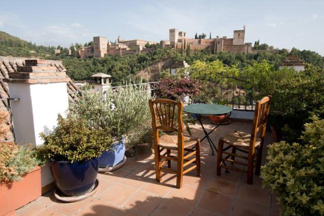 een patio met 2 stoelen en een tafel en een aantal planten bij Casa Victoria in Granada