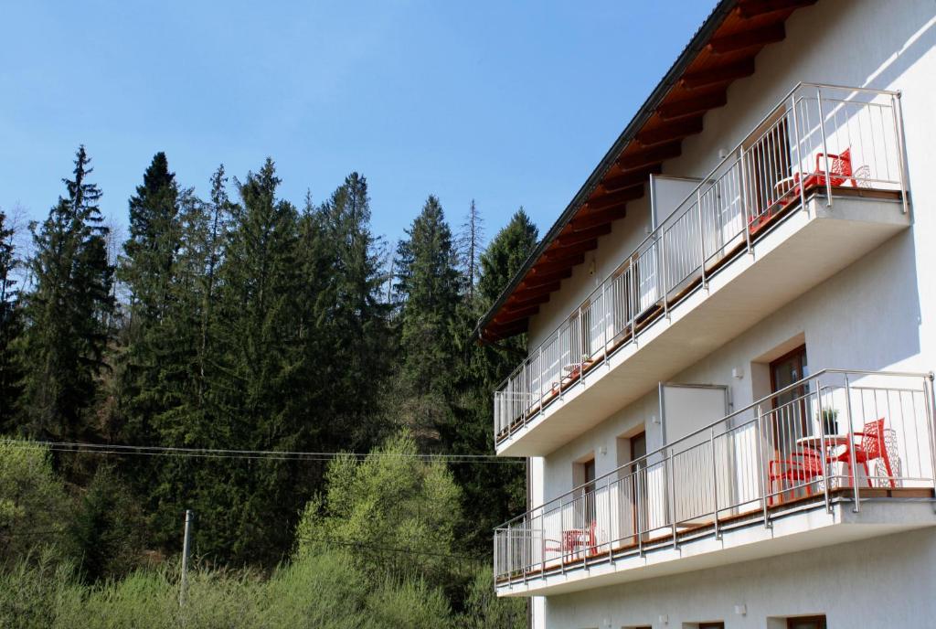 - un bâtiment blanc avec des chaises rouges sur les balcons dans l'établissement Villa Malina, à Oščadnica