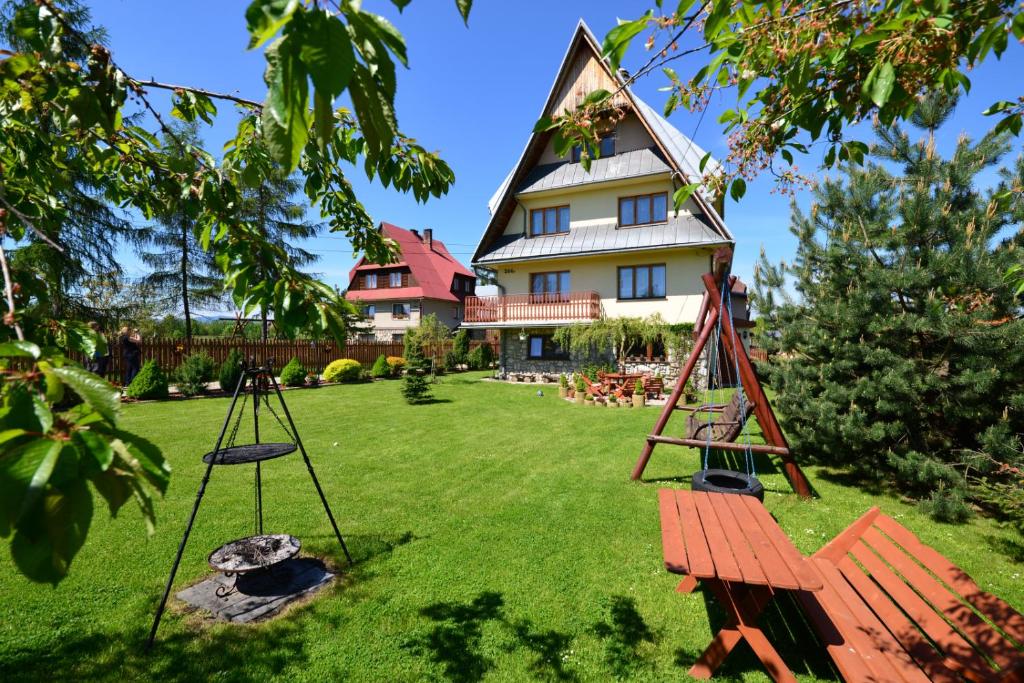 ein Haus mit einem Hof mit Schaukel in der Unterkunft Pokoje Pod Bocianem in Chochołów