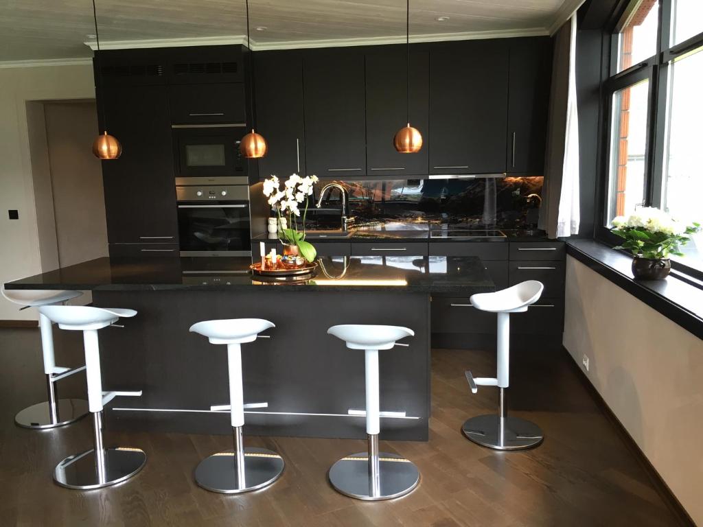 una cocina con armarios negros y taburetes blancos en Olden apartments 1 en Olden
