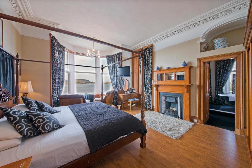 a bedroom with a large bed and a fireplace at Kilchrenan House in Oban