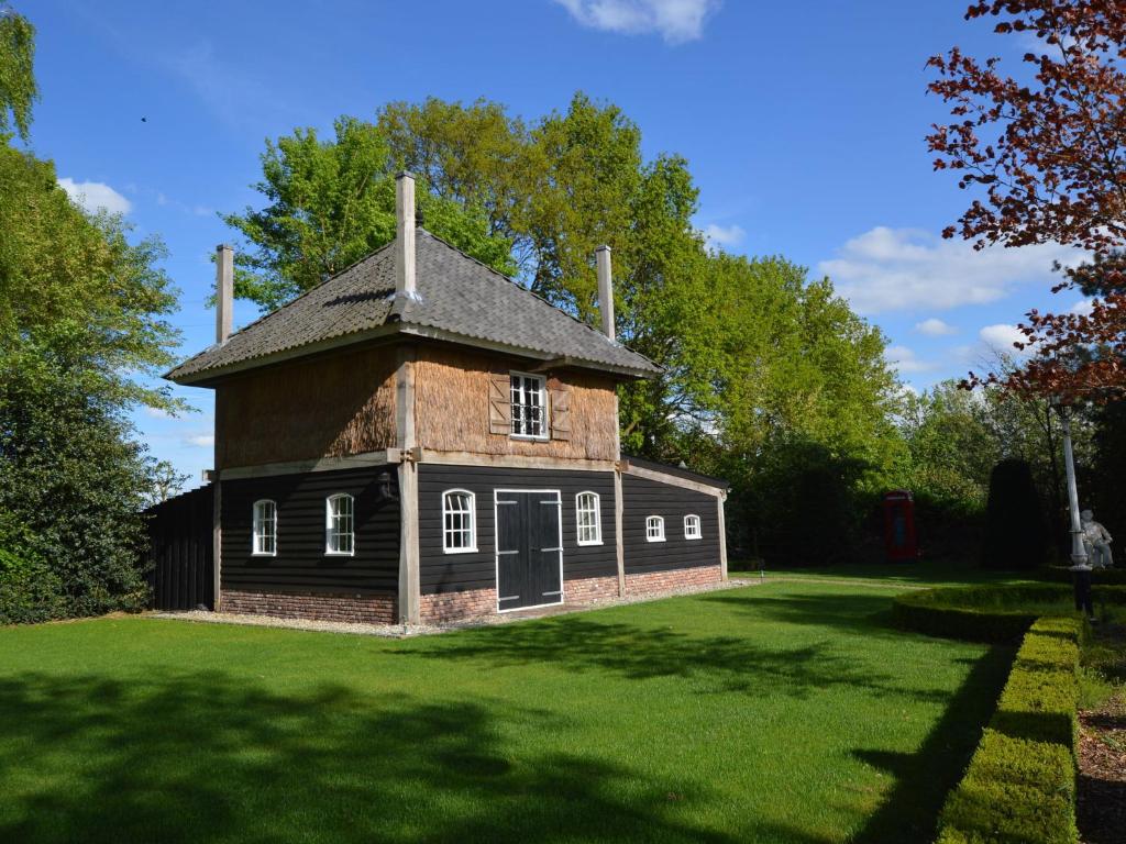 une ancienne maison sur un champ verdoyant avec des arbres dans l'établissement Cozy Holiday Home in Volkel with Sauna, à Volkel