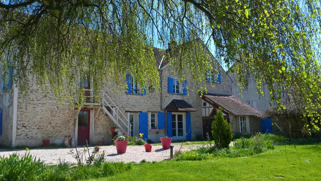 une maison avec des portes bleues et un arbre dans l'établissement gîte du Clos Sébastien, à Beautheil