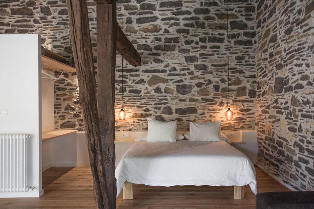 1 dormitorio con una pared de piedra, cama y luces en Izal Landetxea, en Bergara