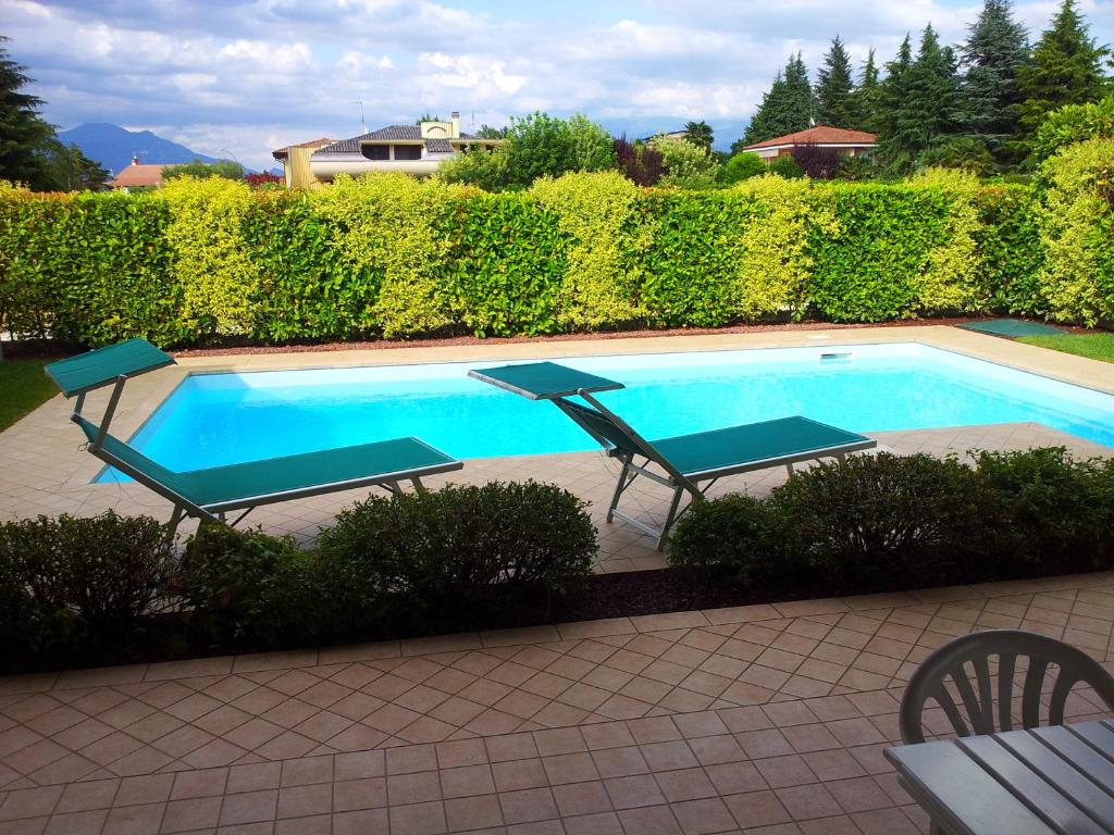 a swimming pool with two lawn chairs and a table at Villa Oliva in Manerba del Garda
