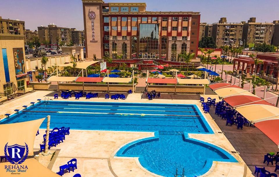 una gran piscina con sillas azules y edificios en Rehana Plaza Hotel en El Cairo