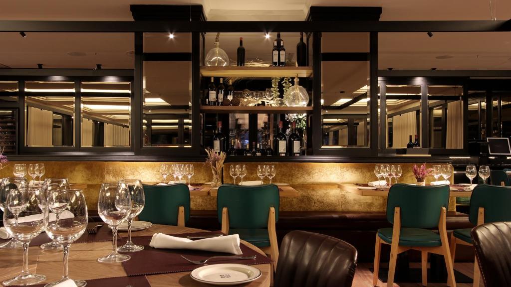 un restaurante con mesa, sillas y copas de vino en Hotel Aretxarte en Zamudio