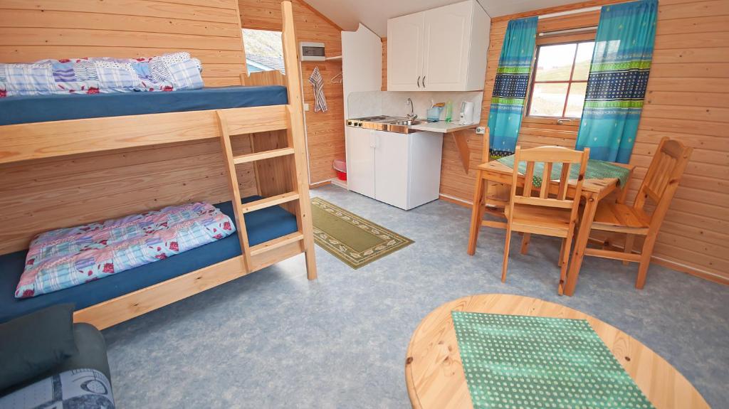 a small room with a bunk bed and a table at Hytte Camp Nordkapp - Blue in Skarsvåg