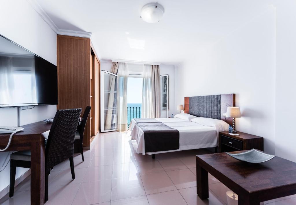 a hotel room with a bed and a table and a desk at Toboso Apar - Turis in Nerja