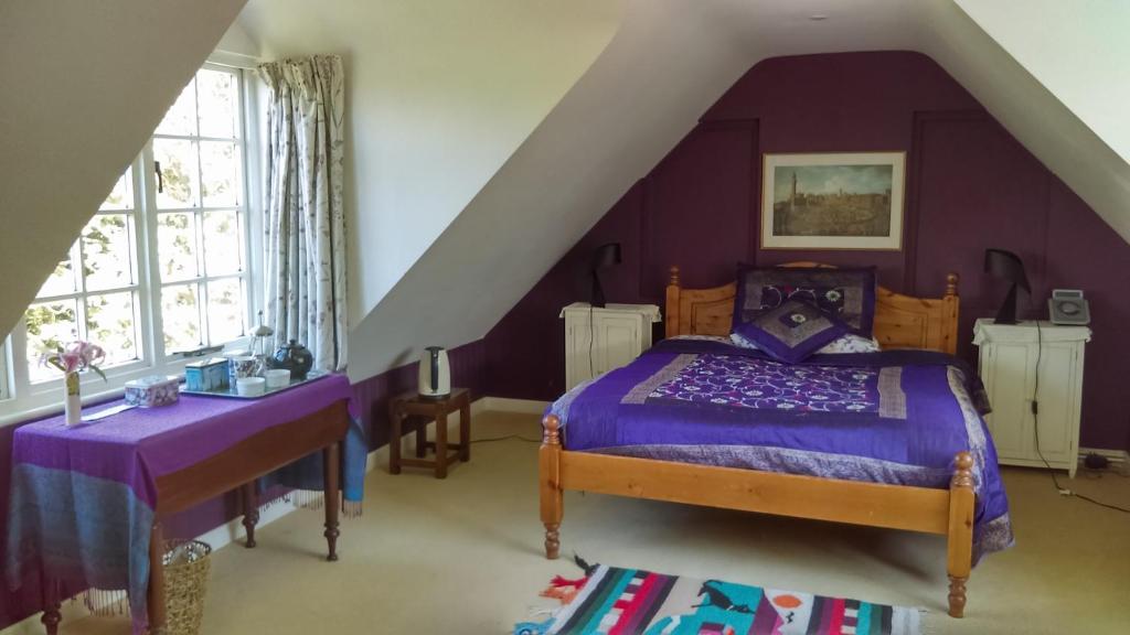 een paarse slaapkamer met een bed en een wastafel bij Orchard Pond Bed & Breakfast in Duxford