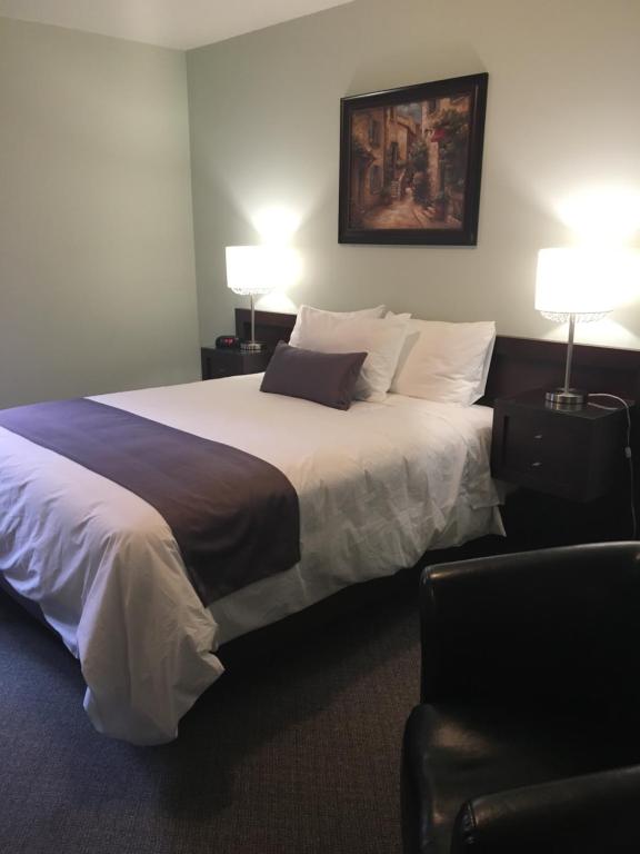 a hotel room with a large bed with two lamps at Auberge Centre Ville in Saguenay