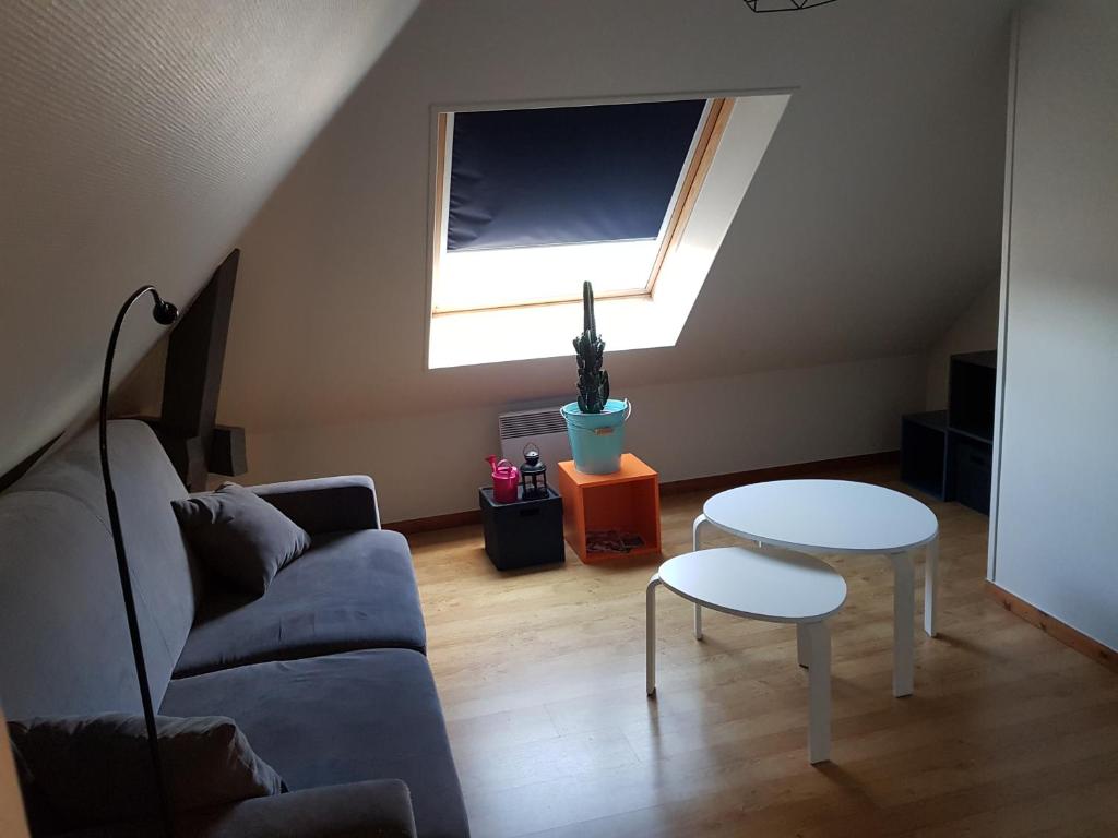 ein Wohnzimmer mit einem Sofa, einem Tisch und einem Fenster in der Unterkunft Appartement Hyper centre - Quartier du château de Vire in Vire